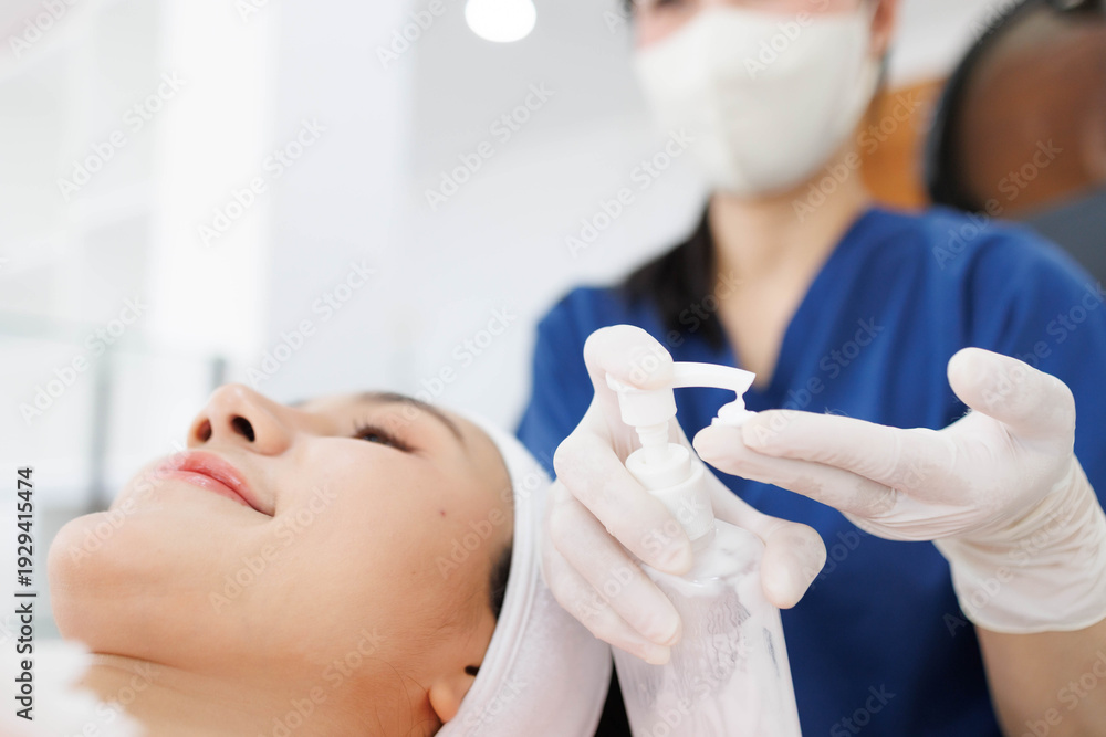 Naklejka premium A woman is getting her face done by a woman in a blue shirt. The woman in the blue shirt is applying makeup to the woman's face 