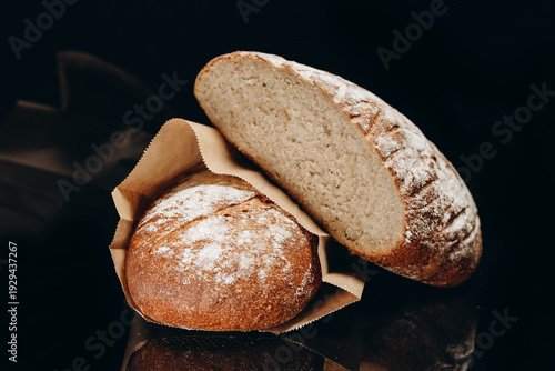 Loaves of rustic artisan bread with flour dusting and crusty interior on black background