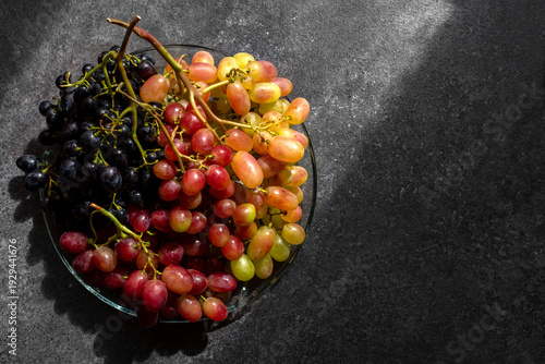 round plate with different varieties of grapes on a dark table copy space on the right