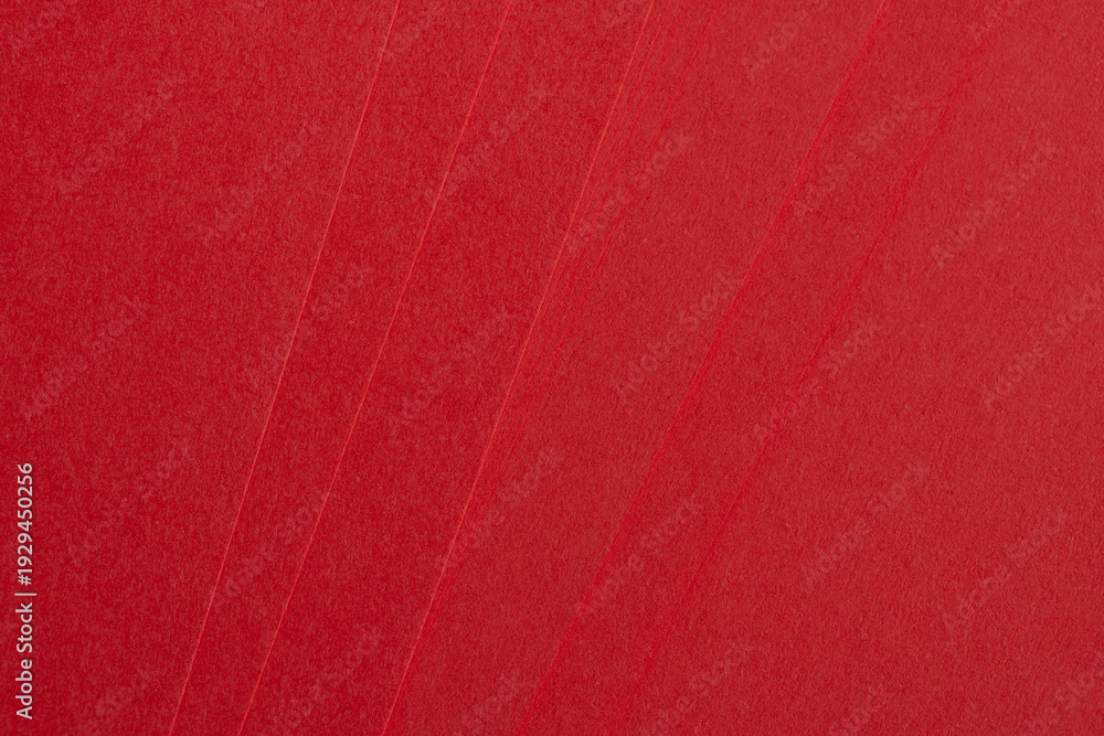 Fototapeta premium Top view of stacked bright red textured paper sheets,Close-up abstract background of multiple layers of vibrant red premium paper with a fine grainy texture, arranged in a fan-like overlapping pattern