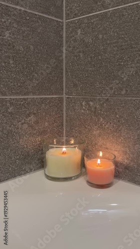 Lighting three candles one by one on the edge of a bathtub. Cozy spa atmosphere, warm soft light and relaxing bathroom mood.