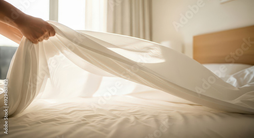 Womans hand making bed with fresh white sheets, clean textile for hotel, spring cleaning, housework, home care, neat, comfort.