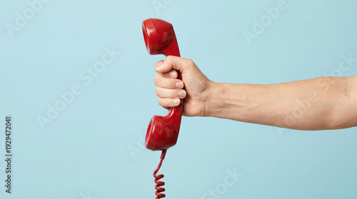 A person holding a classic red vintage telephone receiver against a blue background for customer support concept.