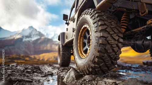 A set of rugged all-terrain tires with aggressive treads mounted on a 4x4 vehicle, navigating a muddy mountain trail, ideal for automotive and adventure themes.