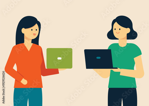 Two businesswomen standing and facing each other, holding laptops, engaging in a professional discussion.