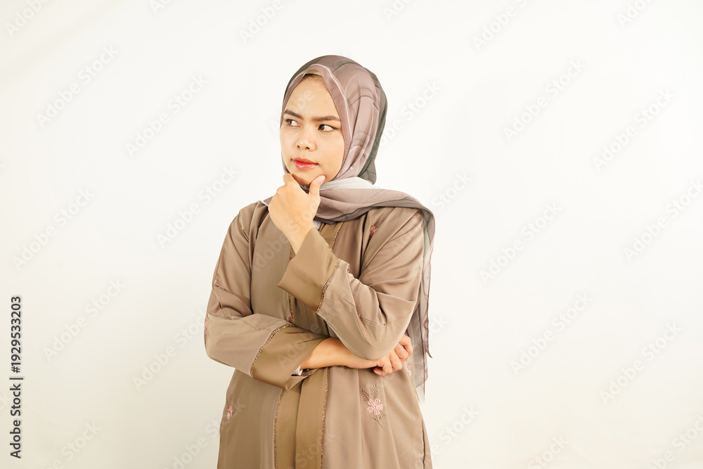 Fototapeta premium Indonesian Muslim Woman Use Headscarf with Thoughtful Expression and Pondering Gesture Isolated on White Background, finger on chin
