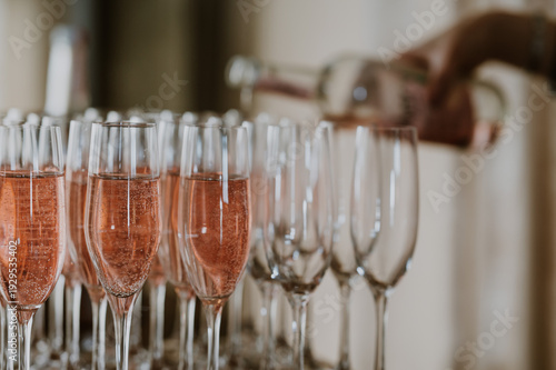 Glasses with pink champagne or non alcoholic fizz being poured in the background with copy space