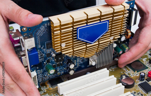 Hands holding computer circuit board with gold heat sink