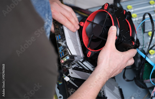 Technician installing red and black computer cooling fan
