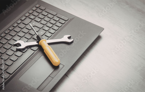 Laptop repair with screwdriver and wrench on keyboard