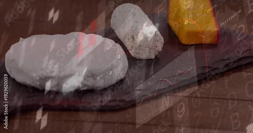 Obraz Showing two-white-ovals and orange-block sitting on dark slate board on wood table with charts