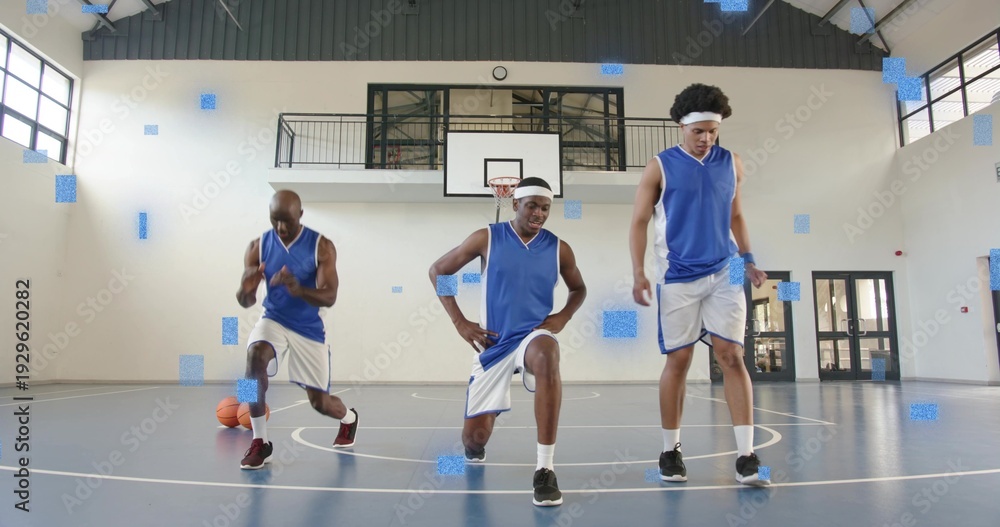 Fototapeta premium Stretching three basketball players in blue-white uniforms doing warmup drills in gym with ball
