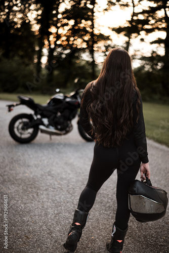 Female motorcyclist riding sport motorcycle at sunset outdoors