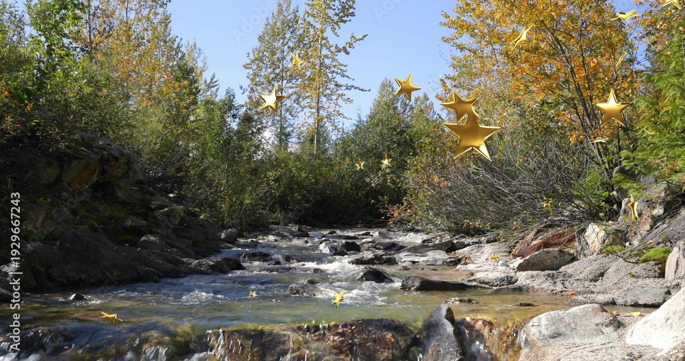 Naklejka premium Flowing shallow creek revealing rocky streambed at sunlit riverbank, with golden star ornaments