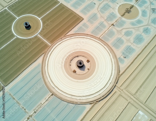 Overhead drone view of circular irrigation pivot systems in geometric agricultural landscape. Concentric circles in beige and sage with electric blue water channels. High-key lighting, minimalist comp