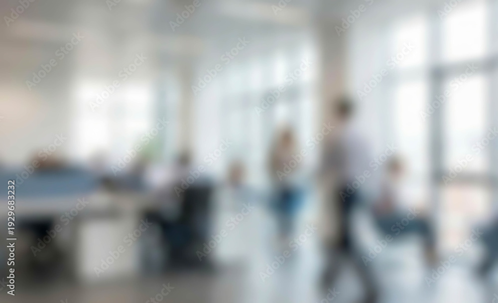 Obraz premium Blurred view of a modern office scene with employees engaged in work. The image shows several individuals at desks, collaborating in a bright, spacious environment.