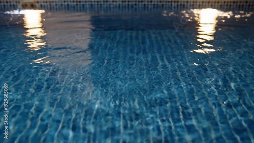 Rippling Blue Swimming Pool Water with Reflections of Lights at Night.