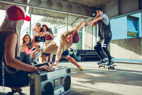 Friends filming street dance and skateboarding at urban skatepark
