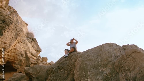 Female Traveler Resting on Stone Rock and Gazing Into Distance in Sunny Weather