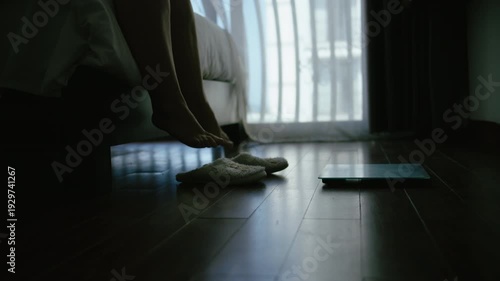 Plus Size Woman Stepping onto Scale in Bedroom at Night