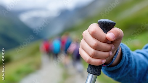 Close-up of child holding hiking stick in mountainous landscape