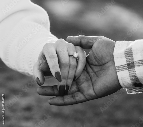 Couple holding hands with engagement ring