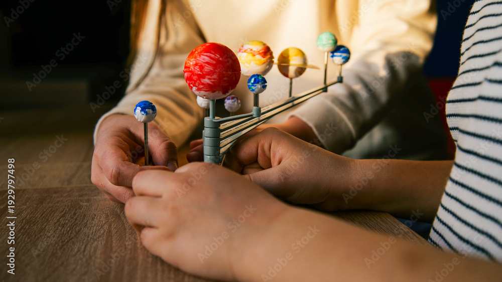 Fototapeta premium Children assembling a solar system model, learning about planets and space exploration