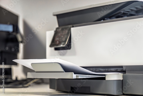 Laser printer with printed documents in output tray office workspace
