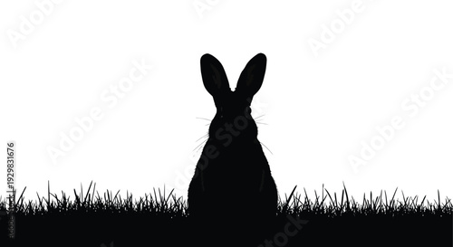 A striking black silhouette of a rabbit sitting in tall grass creating a dramatic and minimalist scene silhouette