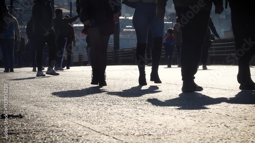 unrecognizable crowd walking on the bridge. the feet and legs of people walking on a busy street. Pedestrians walking in sunny day.