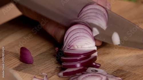 A chef cuts onions for a salad on a cutting board