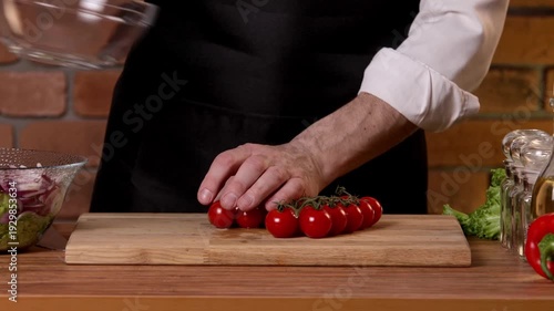 The cook picks tomatoes from the vine to cut them for the salad.