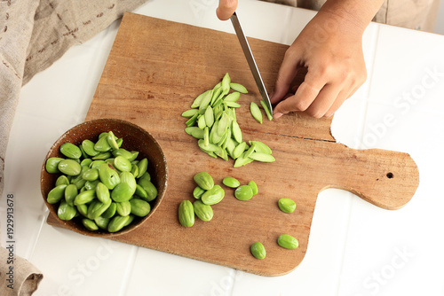Obraz na płótnie Female Hand Cutting and Slicing Fresh Peeled Stinky Bean or Petai