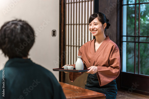 фотографія A female inn staff member serving food at a Japanese inn or Kappo restaurant, a