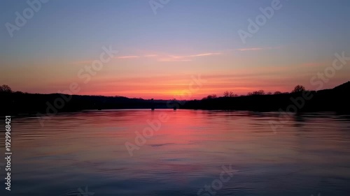 Wallpaper Mural A vibrant sunset paints the sky and water with fiery hues, silhouetting a distant bridge Torontodigital.ca