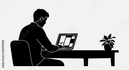 Silhouette of a man working on a laptop at a desk with a plant.