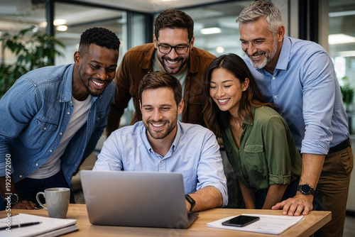 A diverse team looking excitedly at a coworker's laptop screen.