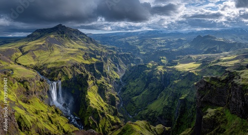 Dramatic Icelandic Canyon - Waterfall Plunges into Verdant Gorge under Stormy Sky.