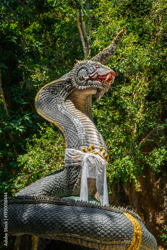 Giant Naga statue in tropical forest at Wat Prangkasi, Thong Pha Phum, Kanchanaburi, Thailand under dramatic sunlight