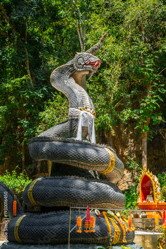 Giant Naga statue in tropical forest at Wat Prangkasi, Thong Pha Phum, Kanchanaburi, Thailand under dramatic sunlight