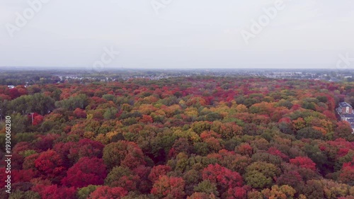 Rotating from left to right above the colorful trees in Fall on a very cloudy day