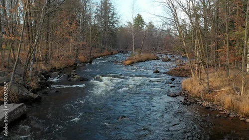 Drone flight mid-air, over the river with small white rapids in the Fall.