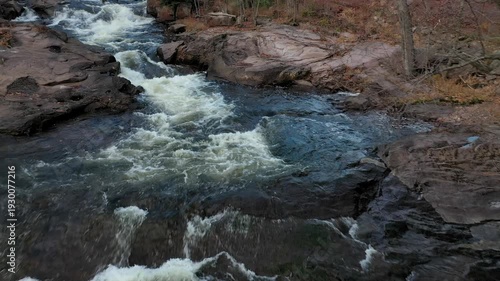 Flying at very low altitude over the rapids, going upstream and following the path of the river.