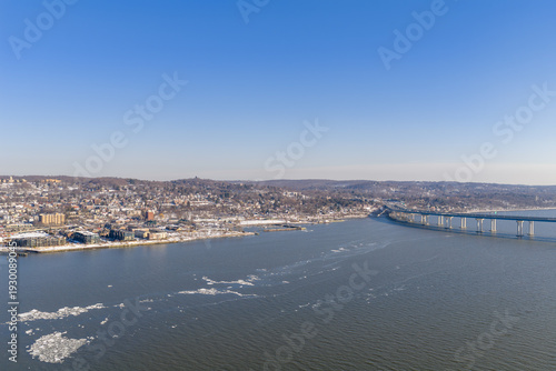 Obraz na plátně The hudson river flows past a snow covered urban landscape and bridge, with ice