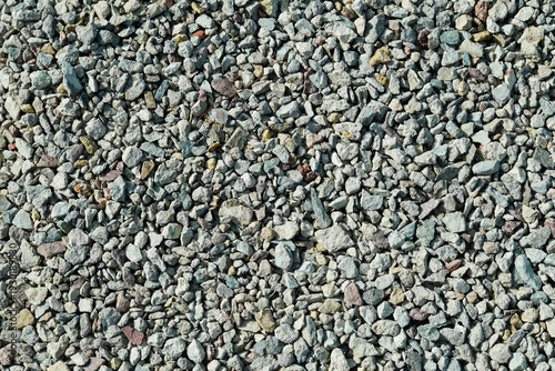 Top view of natural crushed gravel and stone texture. Decorative mixed grey pebble background for landscaping, construction and architectural design.