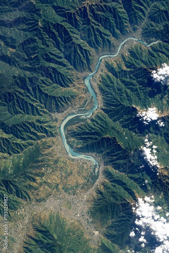 High-altitude view of a river winding through mountainous terrain, with urban sprawl at its banks