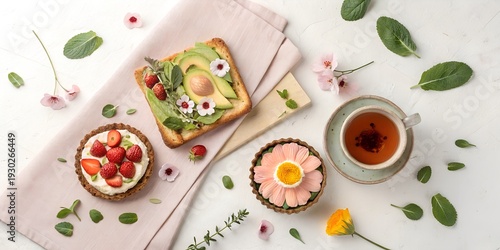 A beautifully styled spring brunch flat lay artisanal toast with avocado and edible flowers, fresh strawberry tart, cup of herbal tea in a ceramic mug, scattered petals and green leaves, linen napkin 