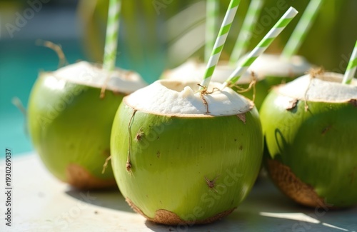 Green coconuts with straws for tropical summer drinks near pool. Refreshing beverage in natural fruit shell, thirst quencher on sunny day.