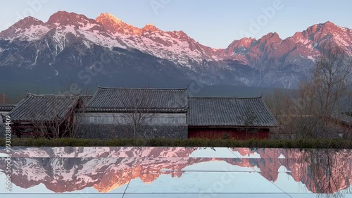 A calm morning lake reflects Jade Dragon Snow Mountain, creating a bright, peaceful scene in Lijiang’s crisp light.