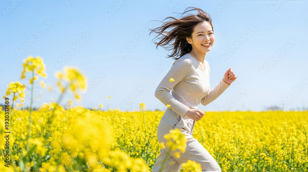 Fototapeta premium 菜の花畑の中を元気よく走る笑顔の女性